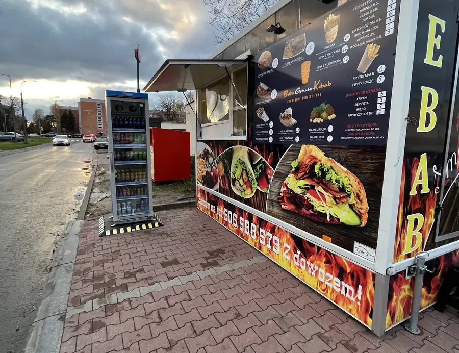 Granatowa budka z napisem KEBAB i tablicą menu